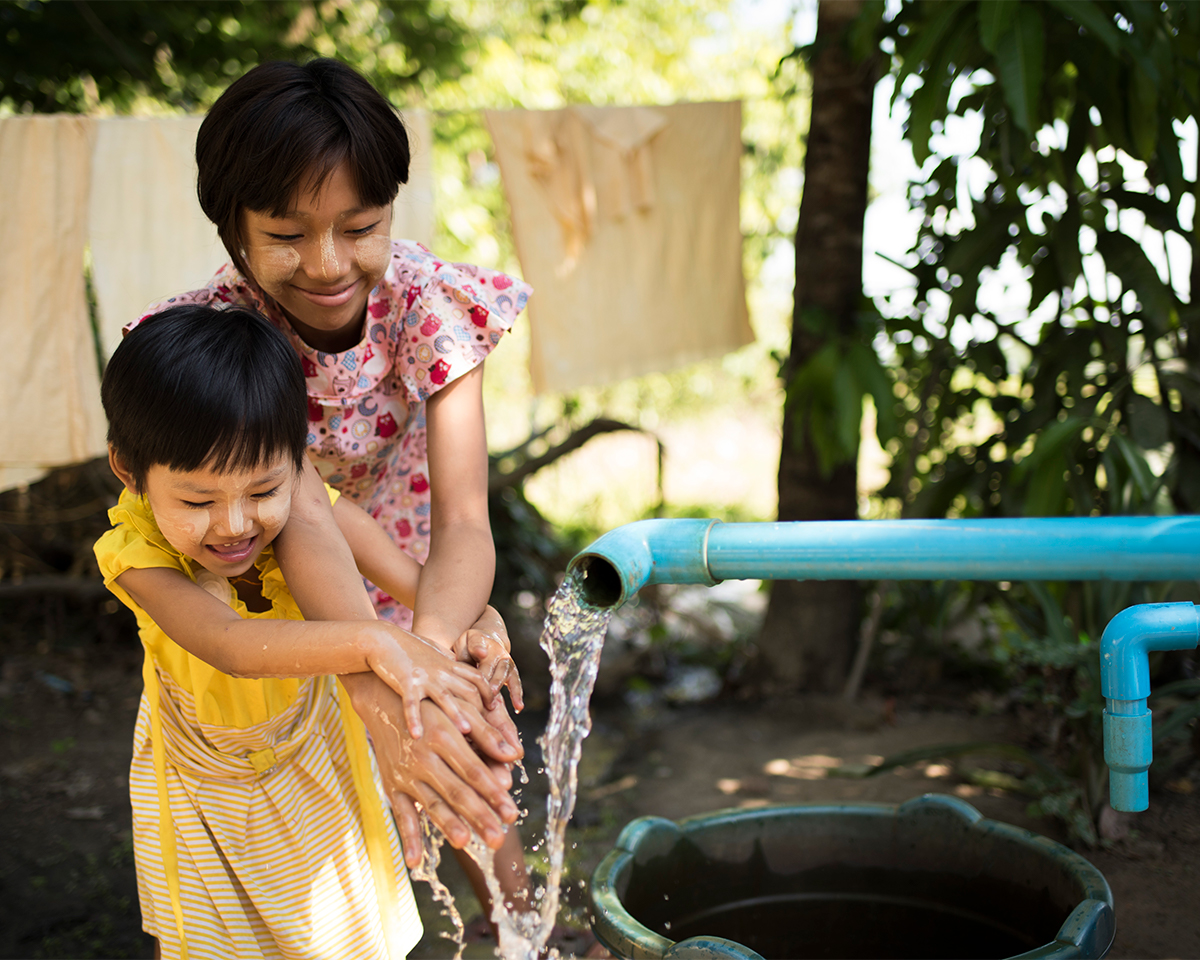 Woman holding a jar full of crystal clear water from a clean well.