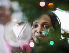 woman placing christmas ornament on christmas tree